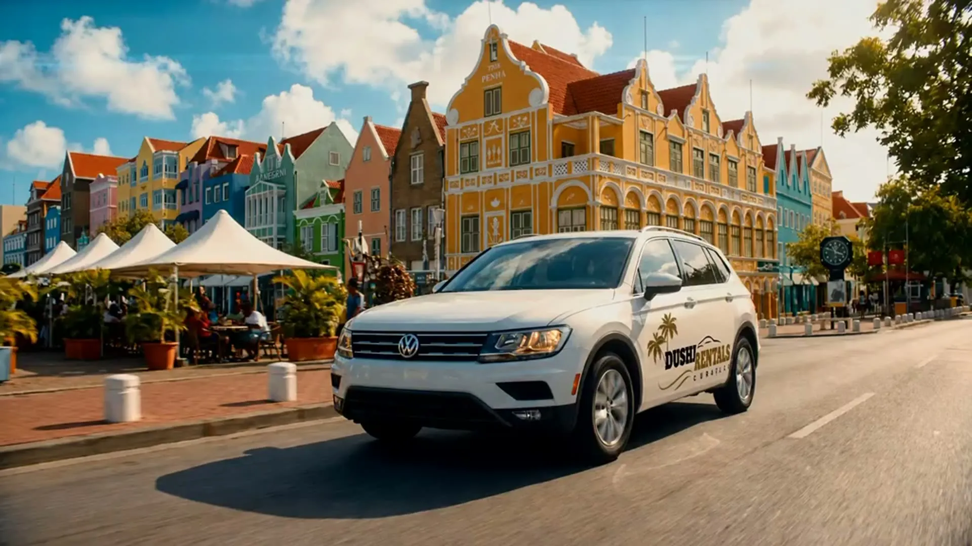 A rental car parked by the water in Curaçao, with the Queen Juliana Bridge behind it